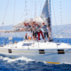 Männer und Frauen winken von einem Segelboot aus.
